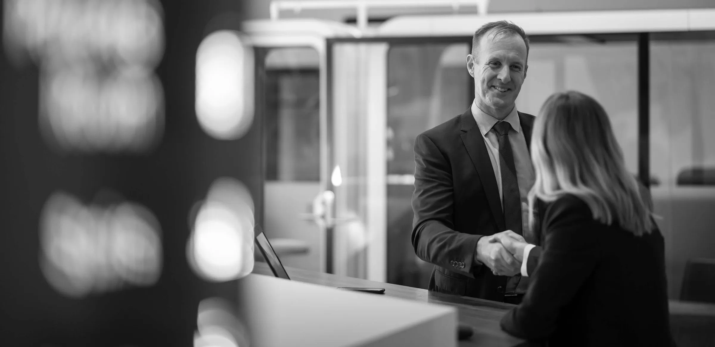A Certified Practising Valuer shaking hands with a client in a modern office
